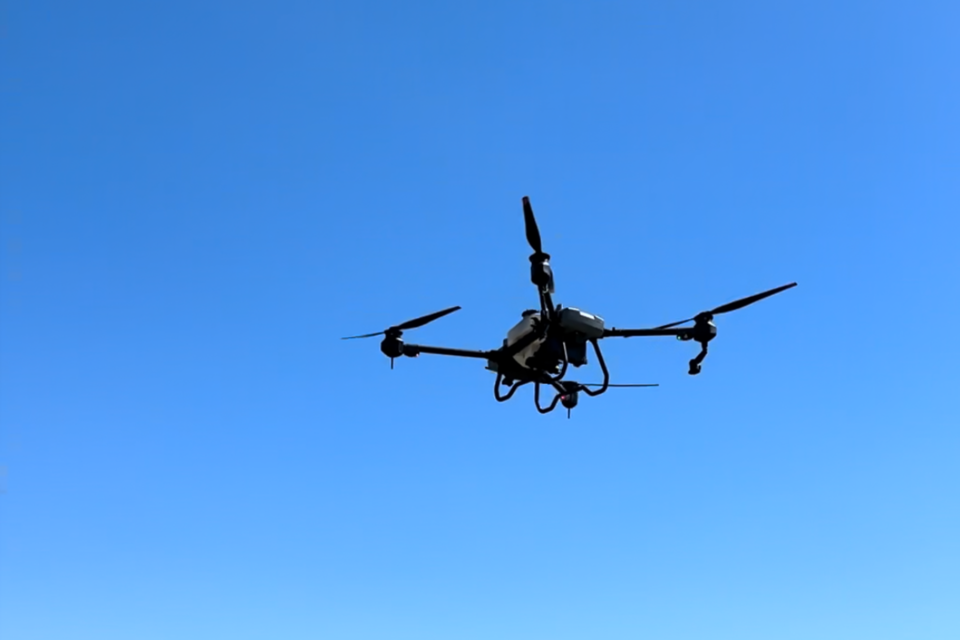 Image of an agricultural drone up close against the blue sky